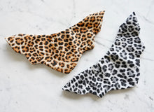 Load image into Gallery viewer, Sweaterly Leopard (Gold): The Sweaterly protects your garment neckline from cosmetic stains in just three simple snaps! This patent-pending design sticks to your neckline without causing pilling, pulling, poking or stretching. Sweaterly is safe on all fabric types and strong enough for most fabric weights. It works on blouses, sweaters, turtlenecks, dresses and even v-necks.
